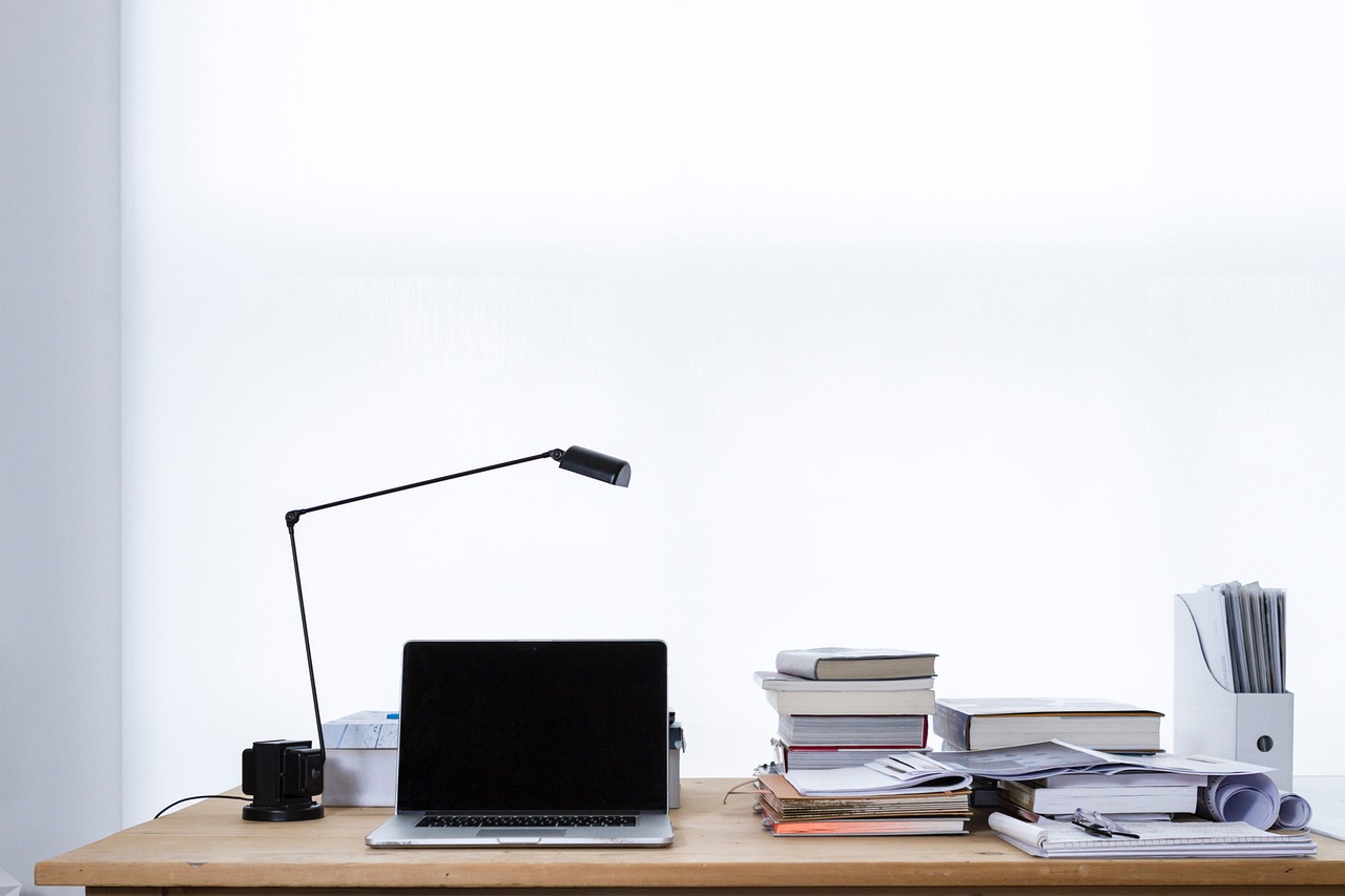 Skrivebord med leselampe, laptop og bøker i en stabel