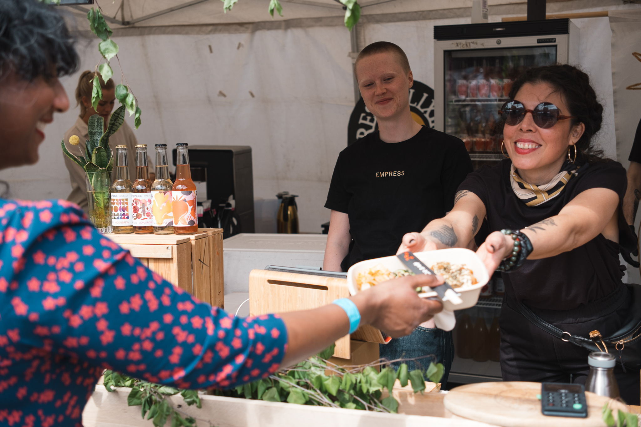 Fornøyd festivalgjest mottar vegetarisk mat fra matbod med blide selgere. 