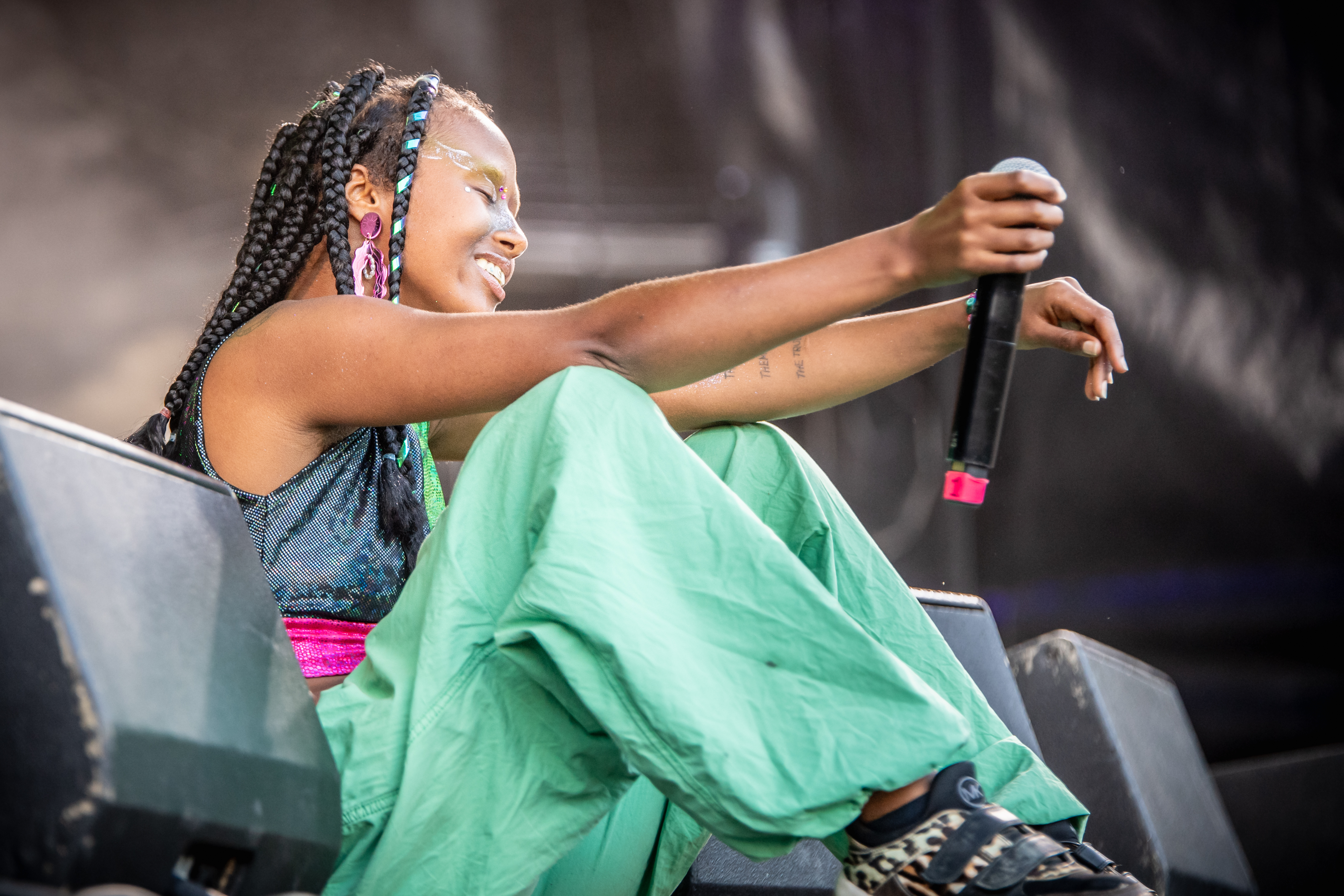 Artisten Ru sitter fornøyd og fredfull, med lukkede øyne mellom monitorer på scenekanten under årets Oslo Pride. Holder en mikrofon i hånda.