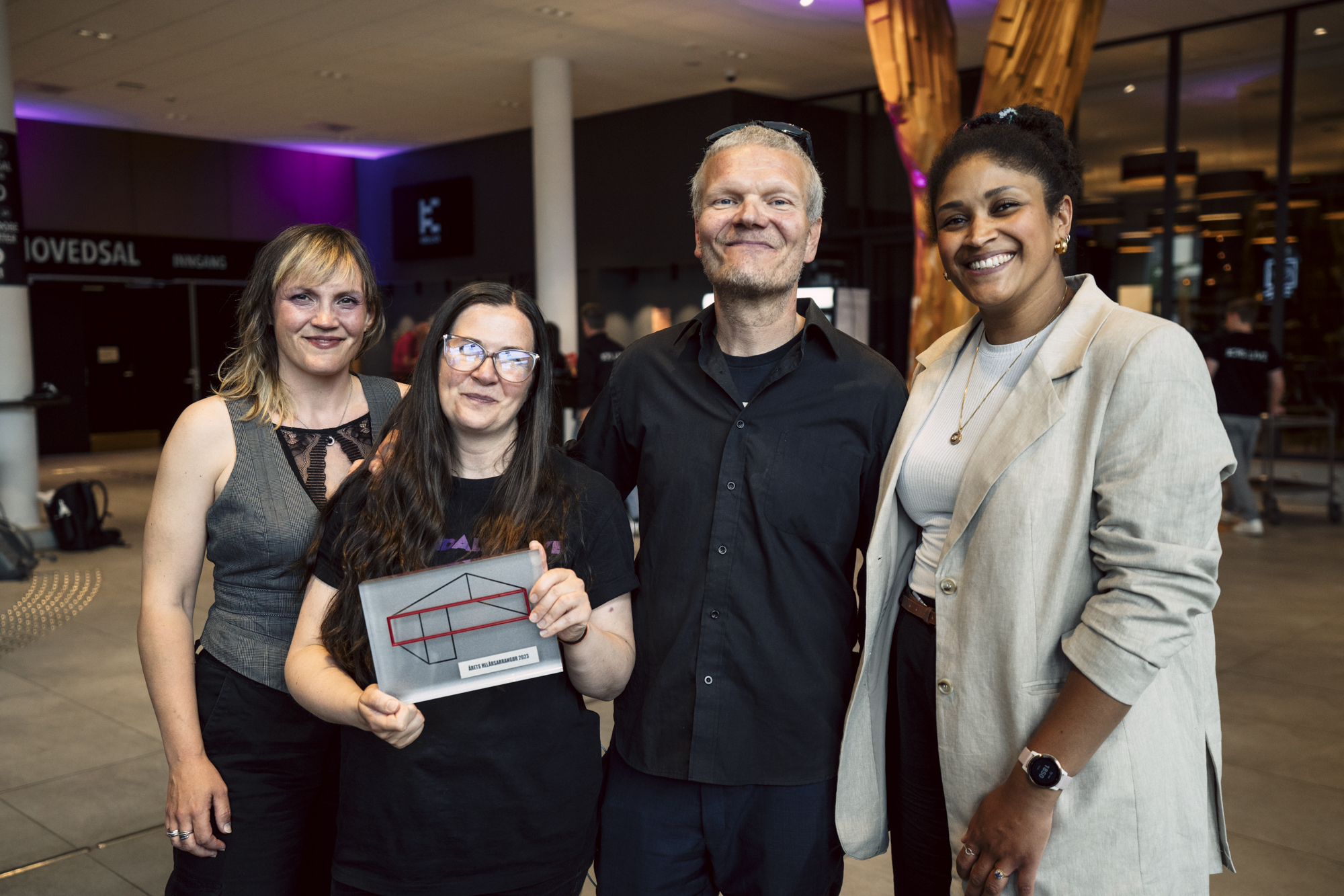 Tre stolte arrangører fra Dirty Old Town og en representant fra NKA smiler fornøyd til kamera. Personen i midten holder stolt frem en plakett for Årets helårsarrangør. 