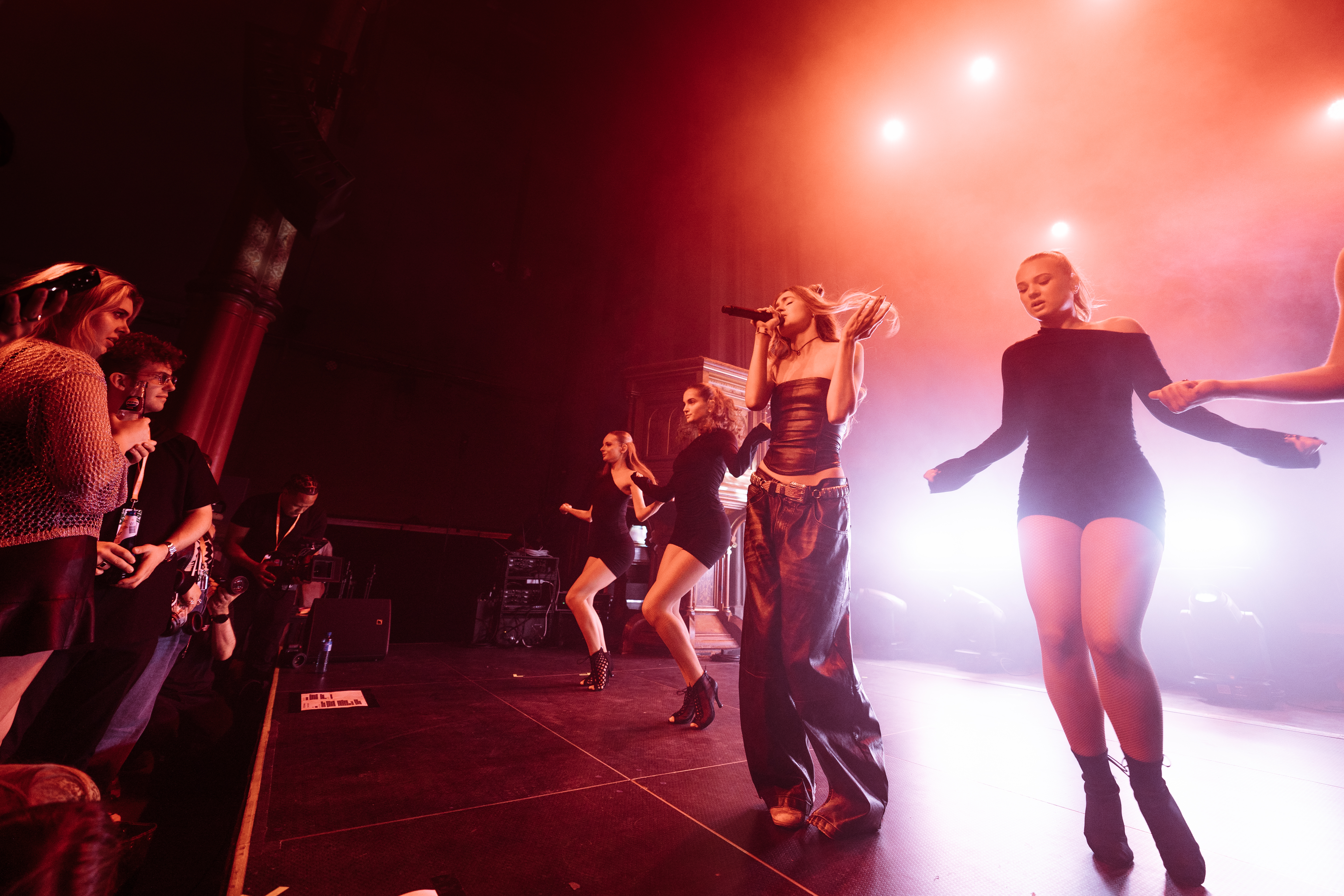 Artisten Kissimjau og fire dansere på en sterkt lyssatt scene leverer et forrykende show under by:Larm i fjor. Foran scenen står flere konsentrerte tilskuere. 