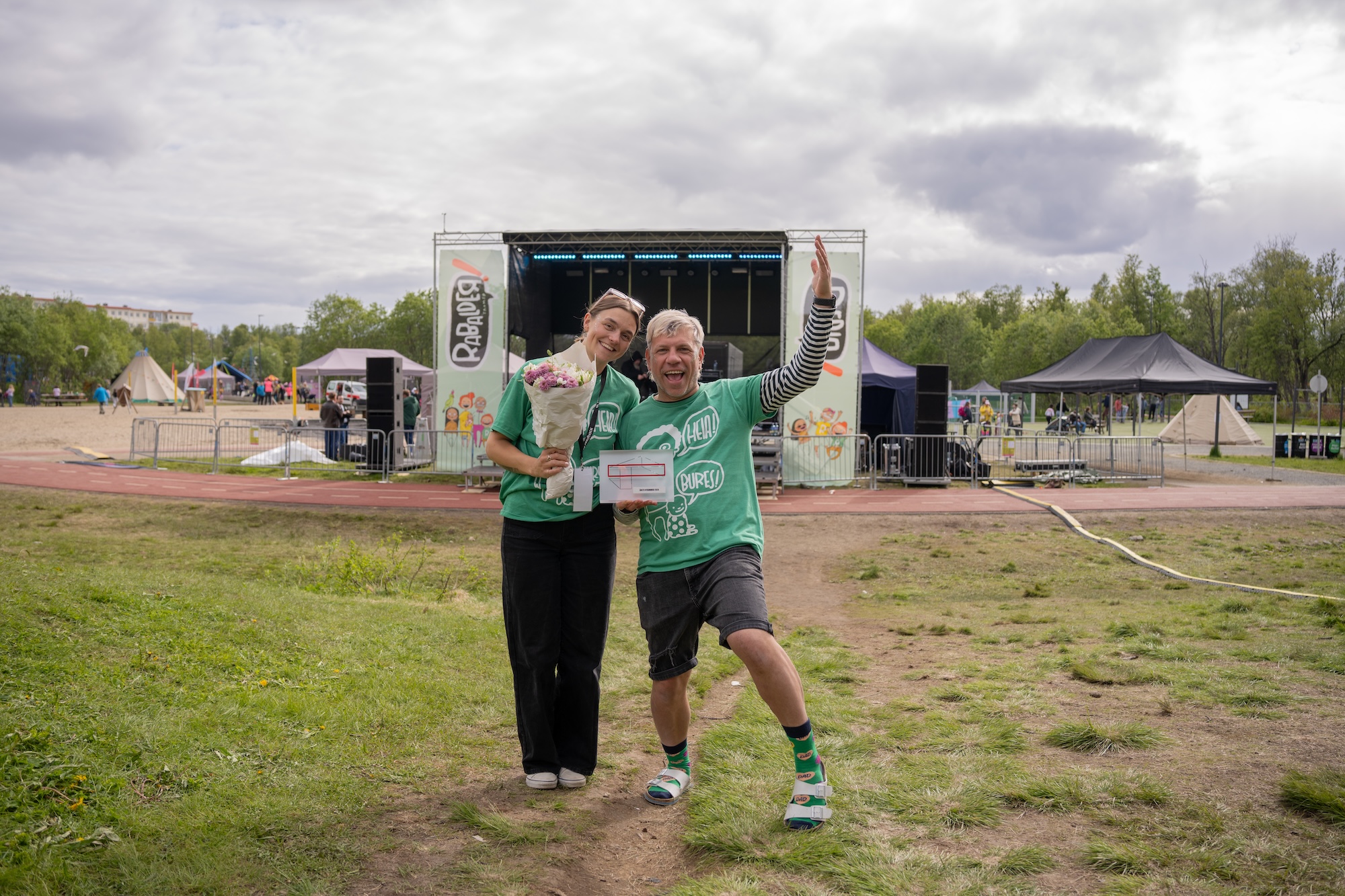 To glade mennesker foran en scene holder en bukett og en pokal.