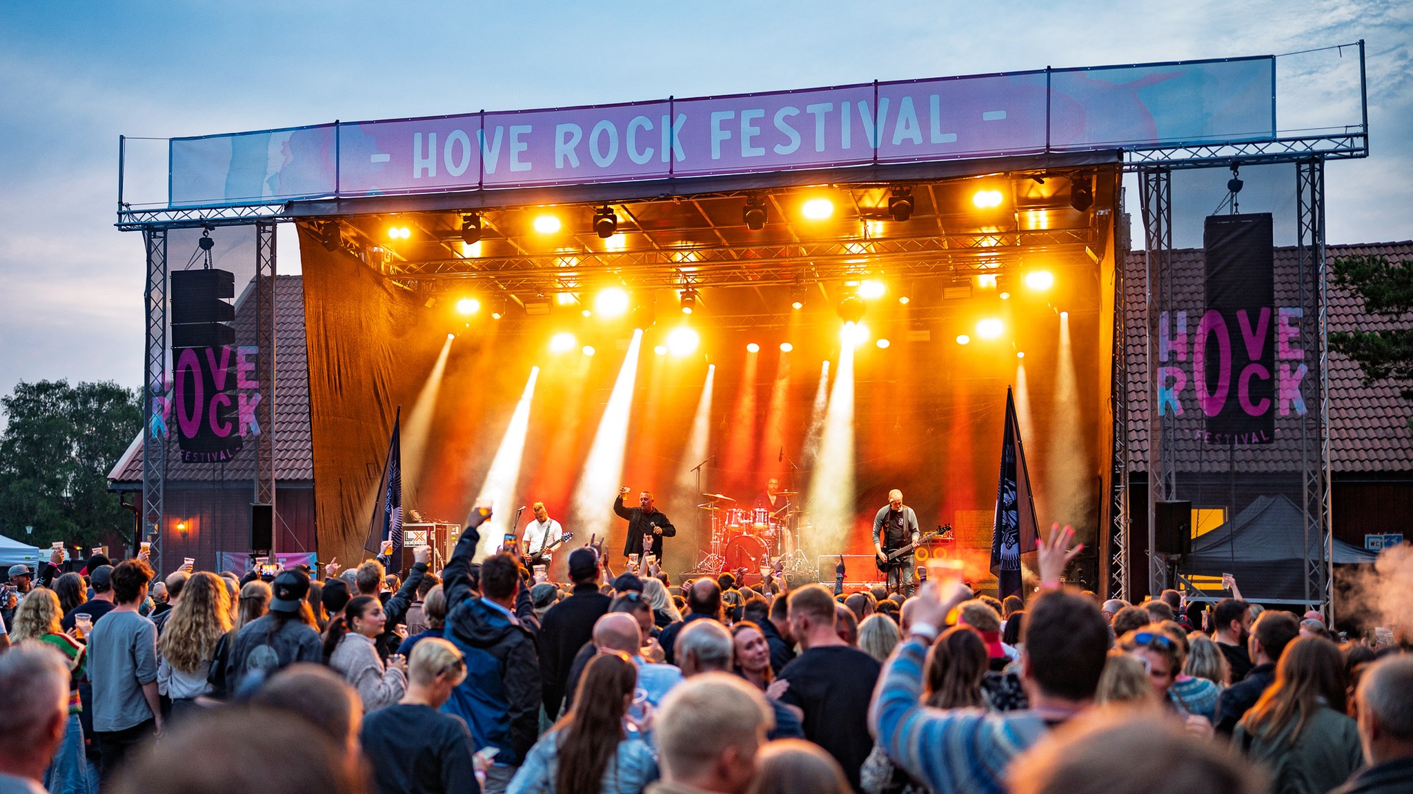 Bildet viser en scene med et band som spiller konsert foran en publikumsmengde.